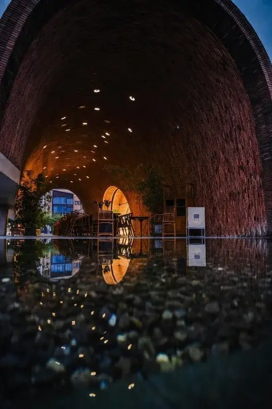 A brick, kiln-shaped vaulted interior at the Jingdezhen Imperial Kiln Museum, reflected in a still pool of water