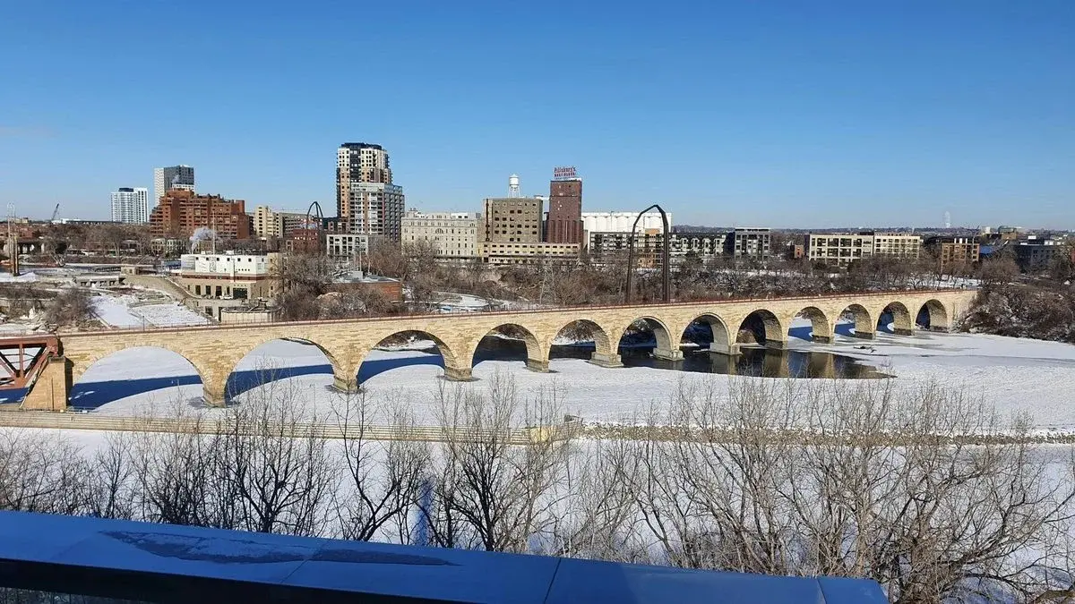 The Stone Arch Bridge over the frozen Mississippi River with the Minneapolis skyline behind