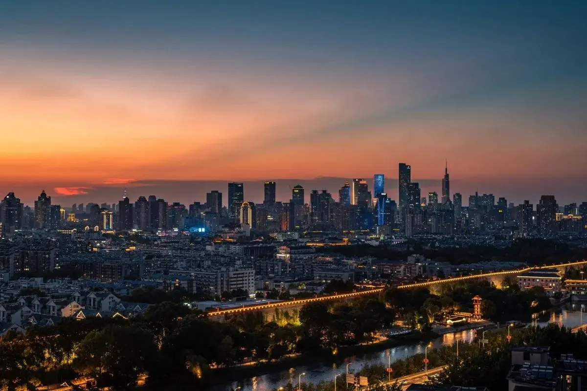 Nanjing's skyline at dusk, the illuminated Ming city wall and moat running along the foreground with the modern downtown towers lit up behind