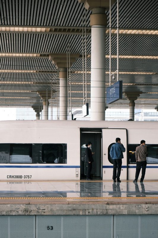 A CRH380B high-speed train at a Nanjing rail platform, passengers boarding under a vaulted station roof