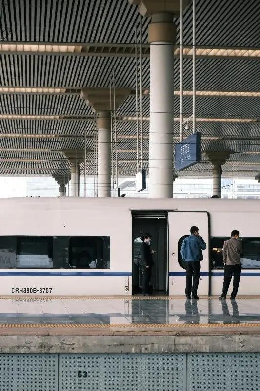 A CRH380B high-speed train at a Nanjing rail platform, passengers boarding under a vaulted station roof