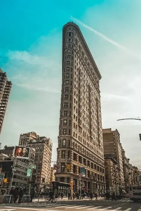 The Flatiron Building's narrow triangular prow rising above a Manhattan street