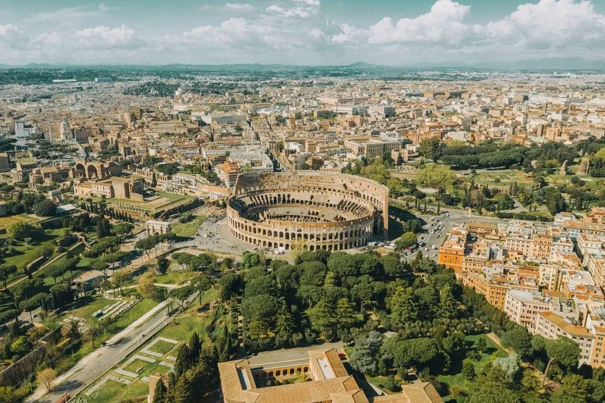 Aerial view of the Colosseum and Roman Forum embedded in the modern city, ringed by streets and traffic