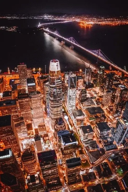 Aerial night view of San Francisco's Financial District and the Bay Bridge lit up over the water