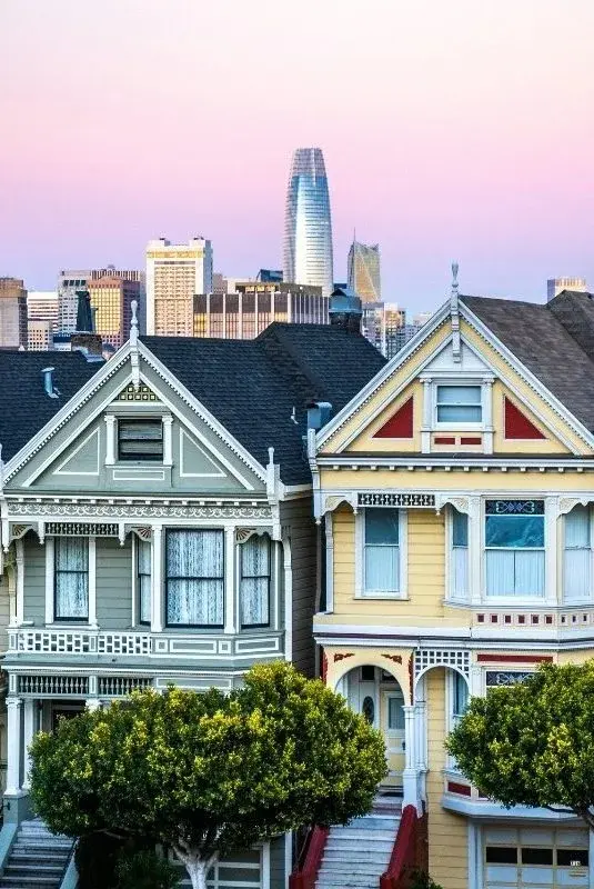 San Francisco's Painted Ladies Victorian houses at dusk, the Salesforce Tower rising behind them
