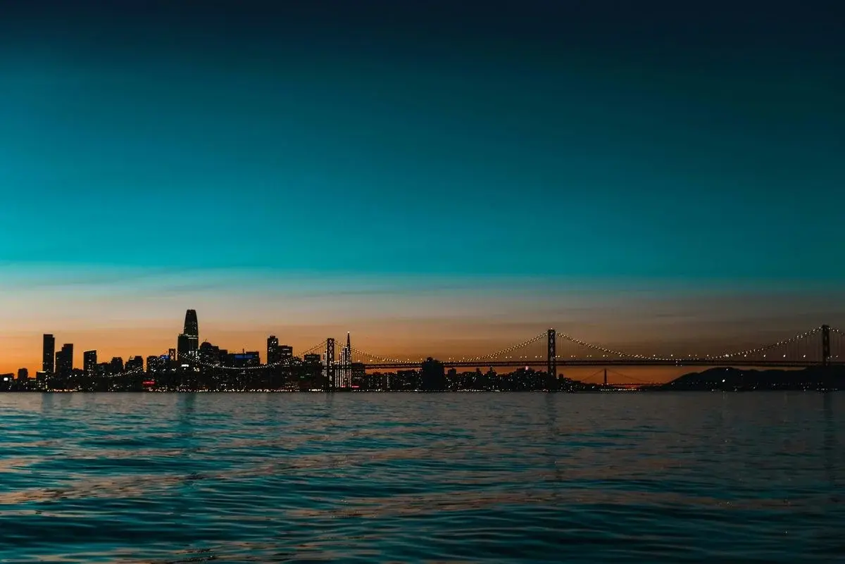 San Francisco's downtown skyline at dusk from the bay, the Salesforce Tower and Bay Bridge against a teal sky