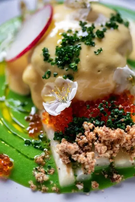 An elaborately plated dish with white asparagus, salmon roe, and edible flowers at a San Jose restaurant