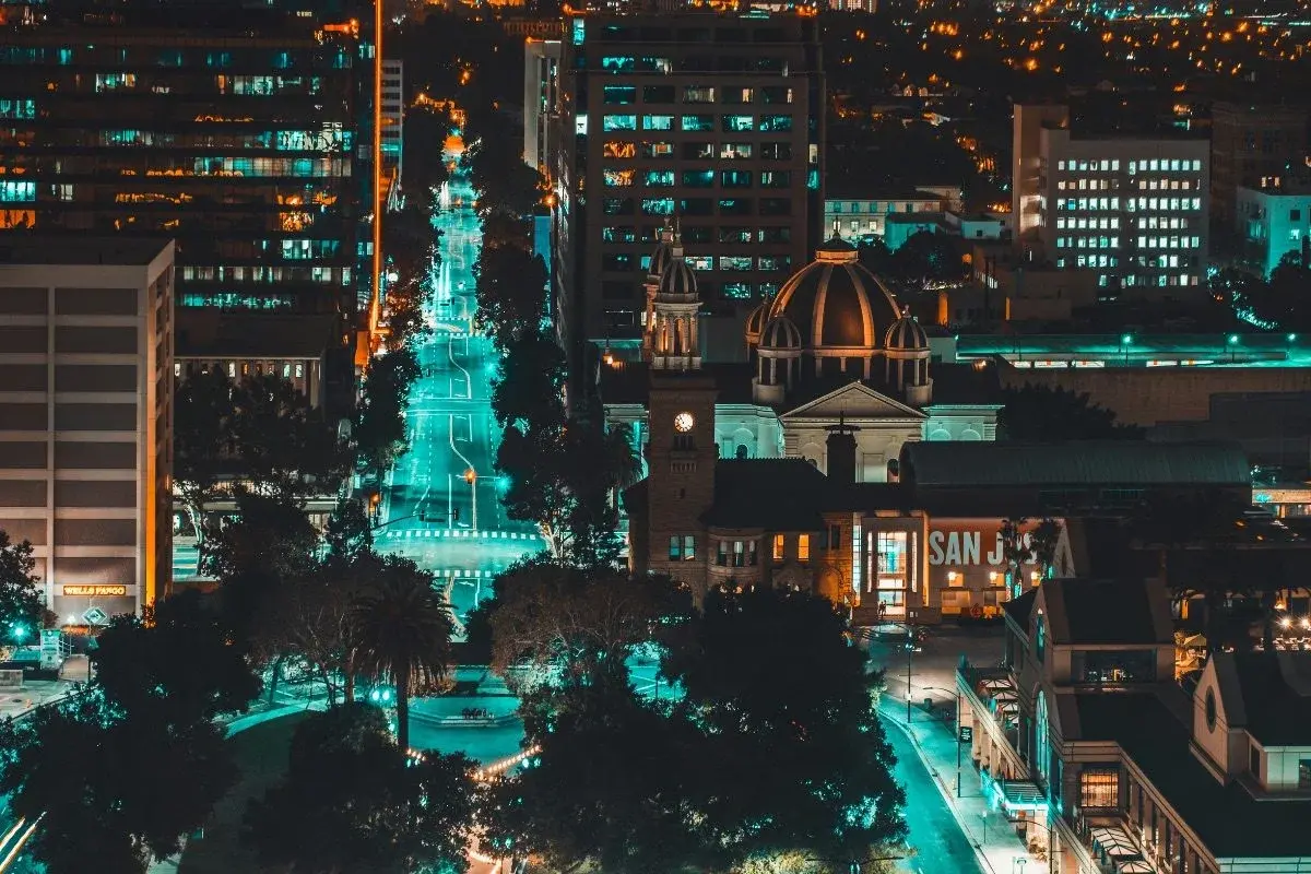 Downtown San Jose at night, glowing teal-lit street leading toward the historic city hall dome