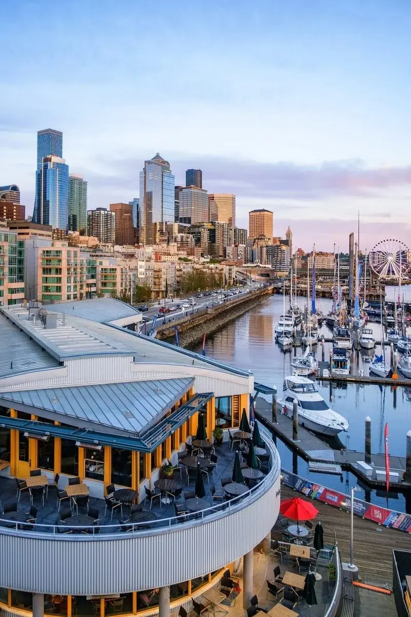 Seattle's waterfront at dusk — marina, sailboats, downtown skyline and the Great Wheel