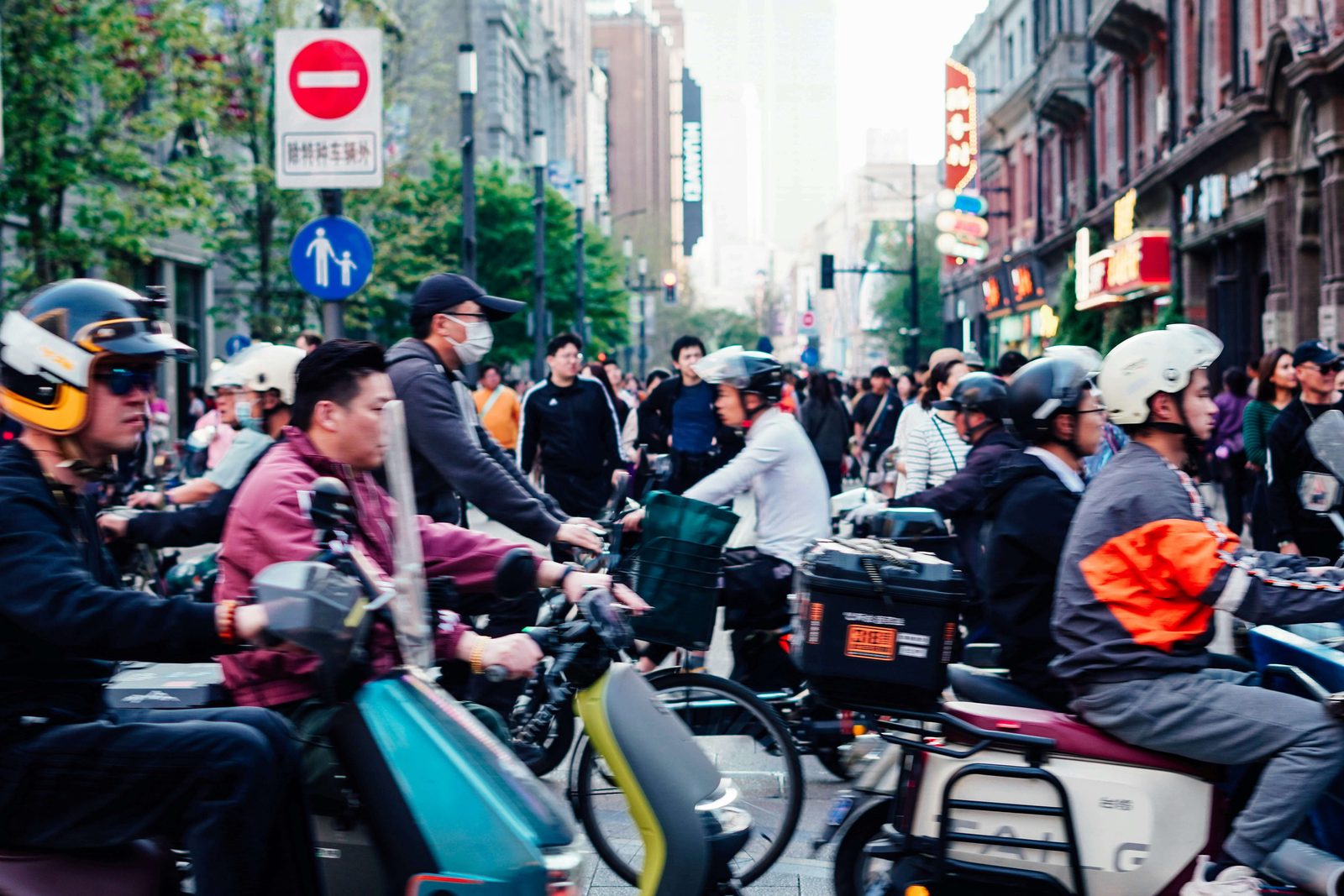 A dense crowd of electric-bike riders and pedestrians on a Shanghai street at dusk