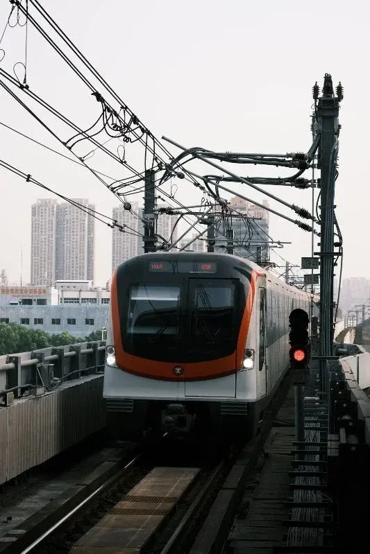 A Shenzhen Metro train arriving at an elevated station, city towers visible behind it