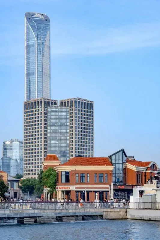 Jinji Lake waterfront in Suzhou with a modern glass skyscraper rising behind a red-brick colonial-style building