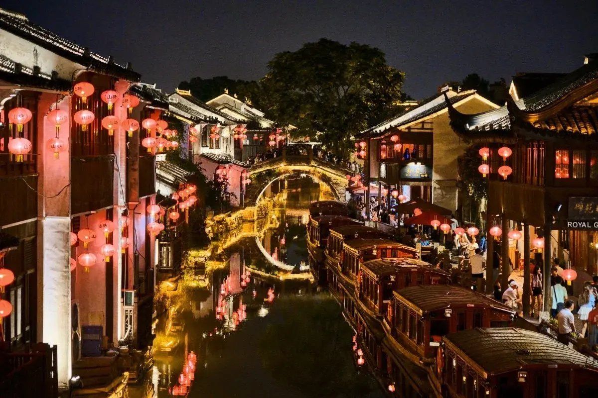 Shantang Street canal in Suzhou at night, lined with red lanterns and wooden tour boats