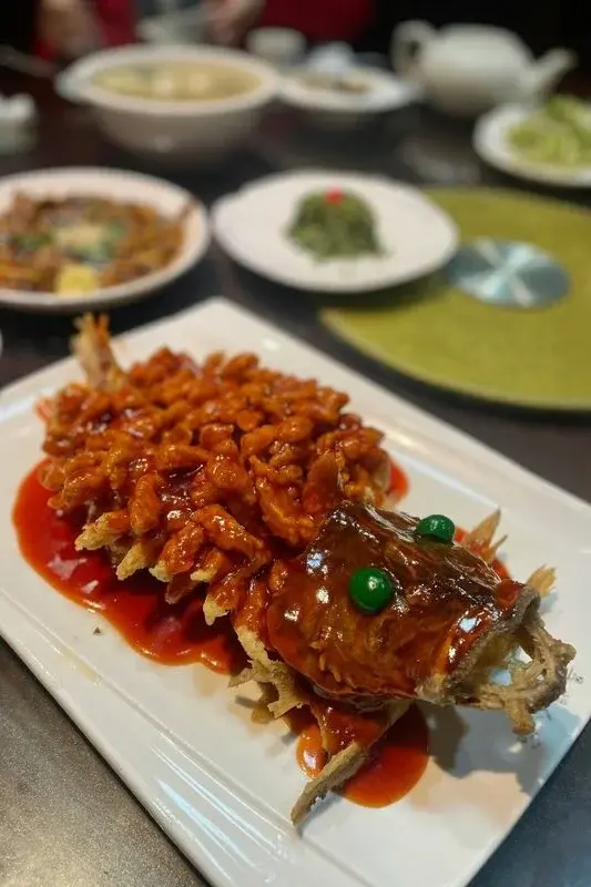 Squirrel-shaped mandarin fish, a classic sweet-and-sour Suzhou dish, served on a rectangular white platter