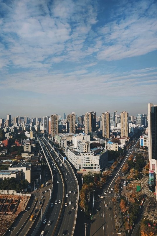 An aerial view of a Wuhan expressway cutting through dense apartment towers under a hazy sky