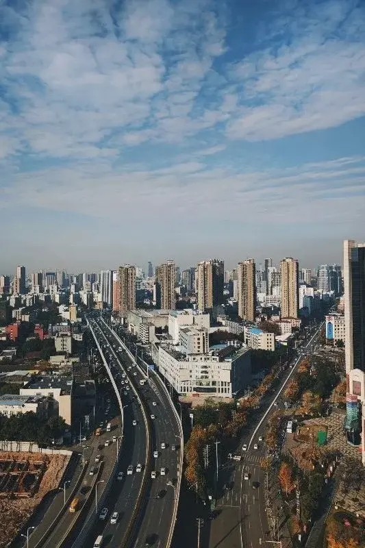 An aerial view of a Wuhan expressway cutting through dense apartment towers under a hazy sky