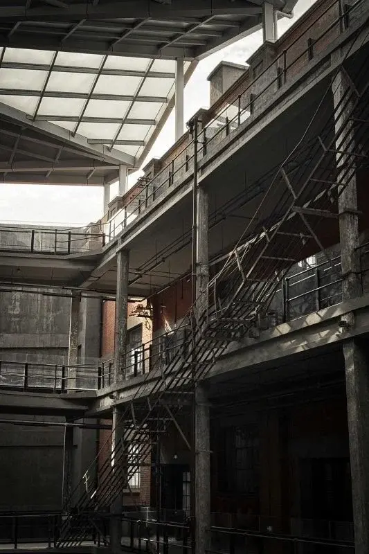 The interior courtyard of a converted Wuhan industrial building, exposed concrete floors, steel walkways and fire-escape stairs