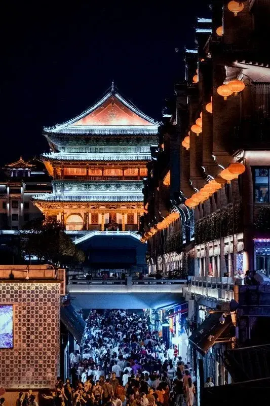 Xi'an's Drum Tower lit up at night above a crowded lantern-strung pedestrian street