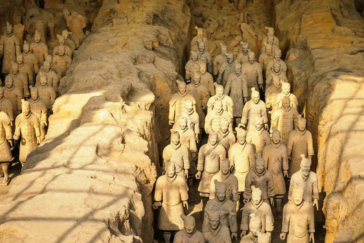 Terracotta warriors standing in golden light in the excavation trenches of Pit 1 in Xi'an
