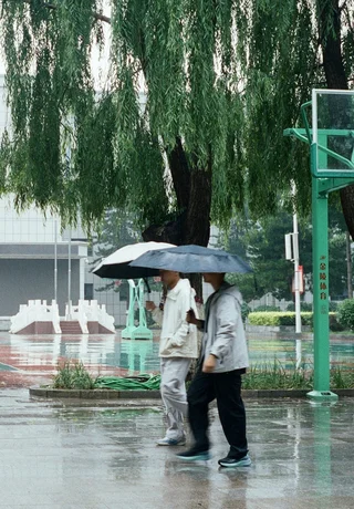 Students with umbrellas crossing a rainy campus in Hohhot