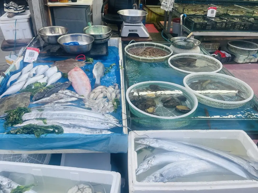 Wet market seafood stall in China with ribbon fish and shrimp laid on ice and clams and snails in water-filled basins
