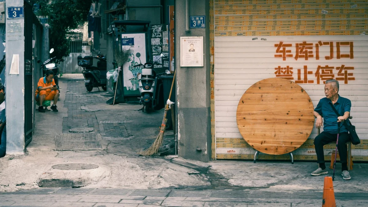 Quiet Chinese residential alley with scooters, a folded table and a seated resident