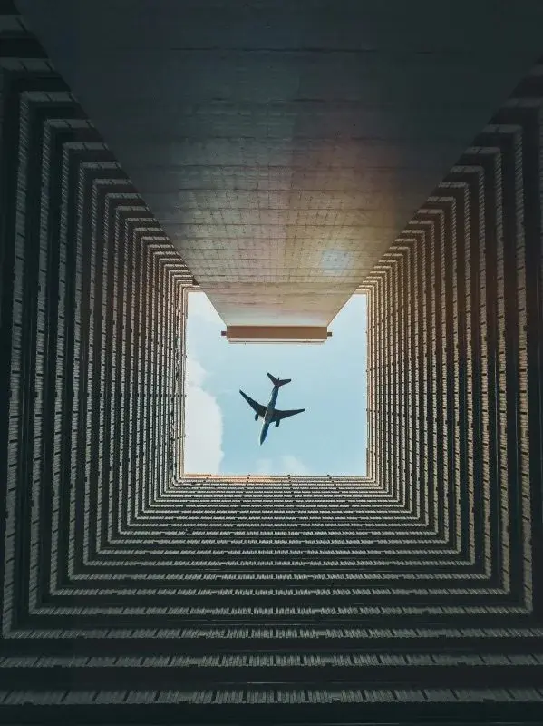 View straight up between residential towers in Hong Kong, with a plane passing overhead