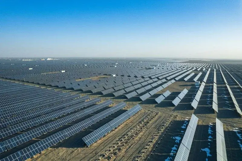 Rows of solar panels spread across flat desert land, seen from above