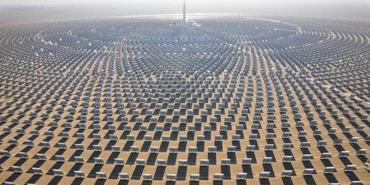 A concentrated solar power tower with a circular array of mirrors spread across the desert