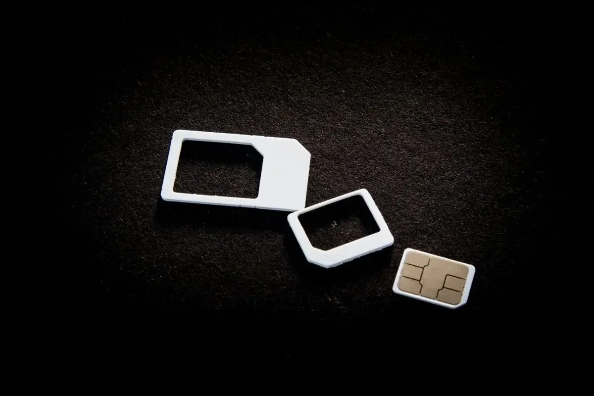 A disassembled SIM card adapter set on a dark background, showing the standard, micro, and nano SIM sizes