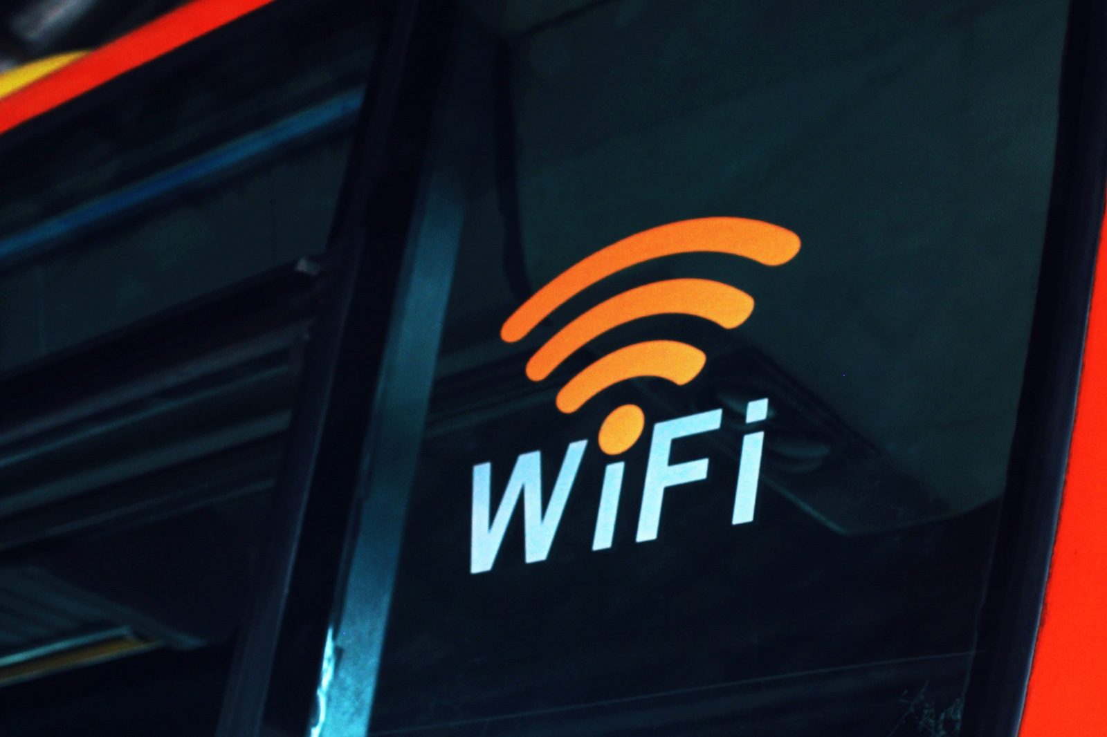 An orange Wi-Fi symbol and lettering displayed on a dark window