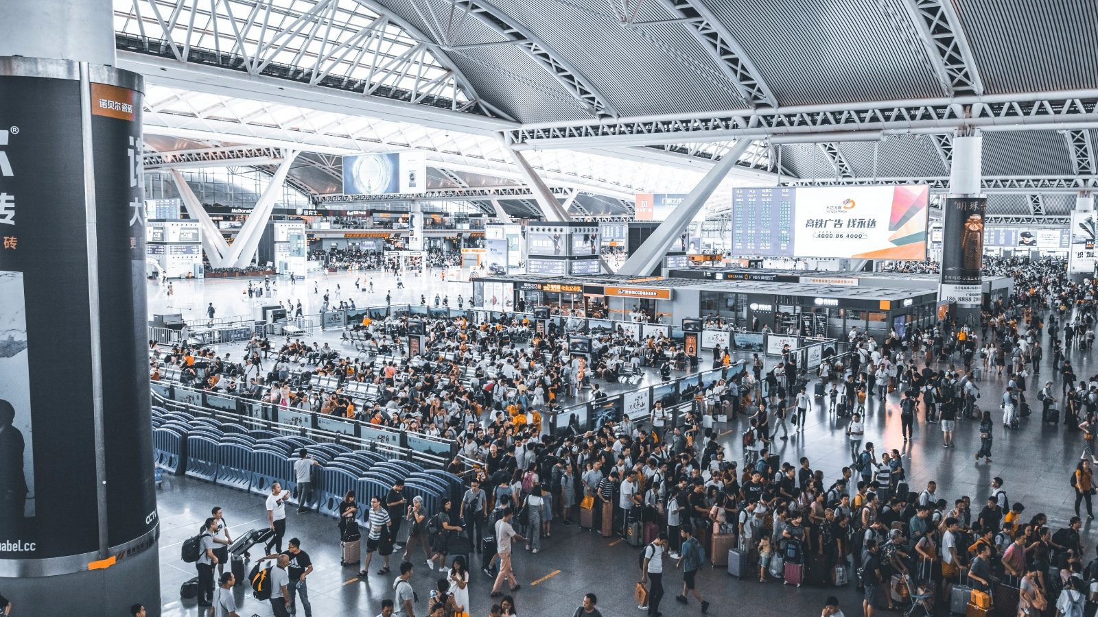 Crowded but orderly interior of Guangzhou South Railway Station with a vast steel-and-glass roof