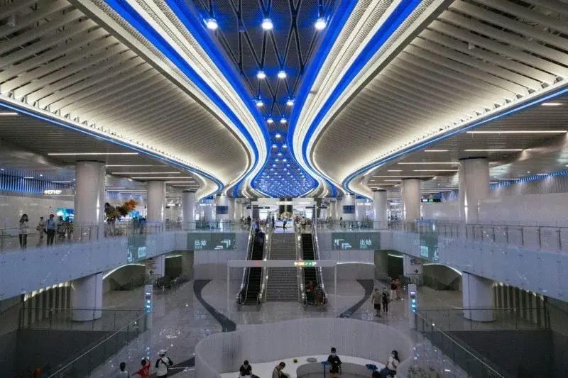 Vast futuristic interior of a Chinese high-speed rail station with a striking tree-like blue-lit ceiling