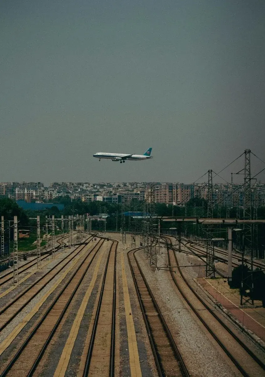 A China Southern plane on approach over a rail yard near a city skyline