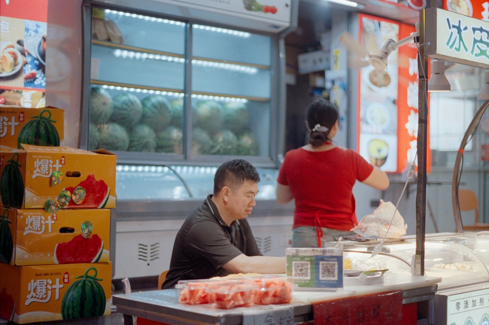 A fruit stall with a printed QR payment code displayed at the counter