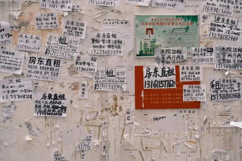 A wall covered in dozens of handwritten Chinese rental advertisements, phone numbers, and 'landlord direct, no agency fee' notices