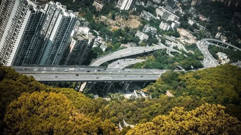 Aerial view of a multi-level elevated highway winding through hilly, forested terrain in Chongqing