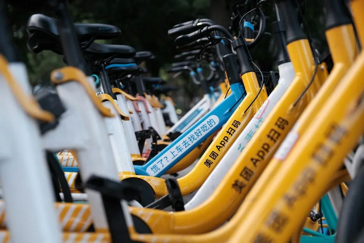 Row of parked yellow Meituan and Hellobike shared bikes with app-scan branding visible