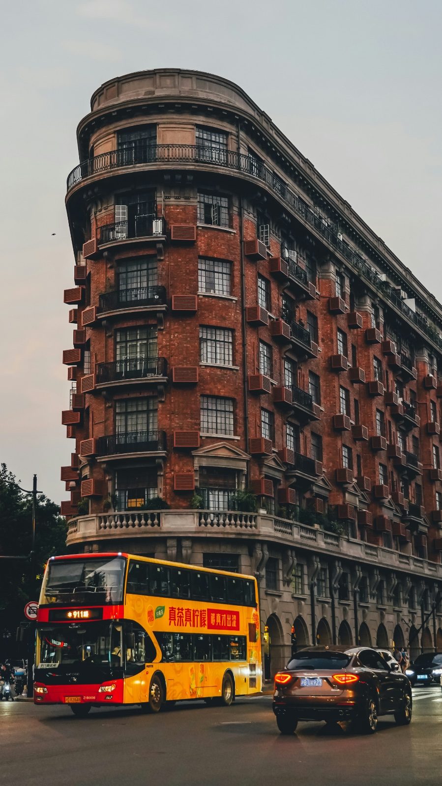 Yellow double-decker sightseeing bus, route 911, passing a brick heritage building