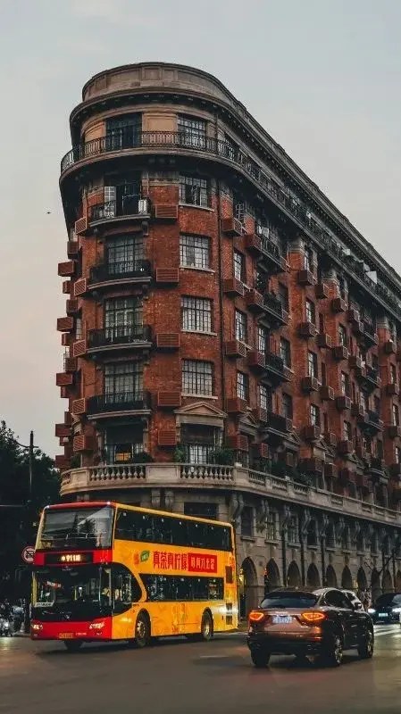 Yellow double-decker sightseeing bus, route 911, passing a brick heritage building