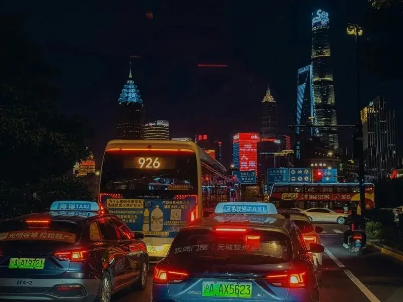 Taxis in traffic at night in Shanghai with the Lujiazui skyline lit up in the background